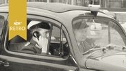 Polizist telefoniert im Polizeiwagen (1960)  
