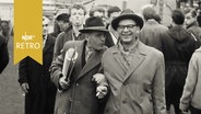 Hamburger Dombesucher 1960: Älteres, vergnügtes Paar, dahinter Halbstarker, der der Kamera die Zunge rausstreckt  