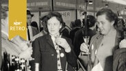 Frauen verkosten Wein an einem Messestand (1965)  