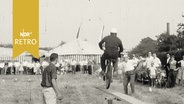 Mopedfahrer auf einem Geschicklichkeitsparcours bei der Fahrt über eine Holzwippe (1961)  