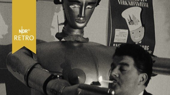 Mann zündet an der Hand eines Roboters eine Zigarette an (1965)  