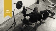 Hammerwerfer Uwe Beyer 1965 beim Training im Kraftraum mit Gewichten  