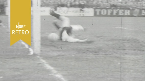 Torwart von Schleswig 06 streckt sich vergeblich nach dem Ball eines Spielers vom Heider SV (1960)  