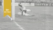 Torwart von Schleswig 06 streckt sich vergeblich nach dem Ball eines Spielers vom Heider SV (1960)  