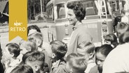 Gruppe von Kindern mit einer erwachsenen Frau vor einem Bus (1961)  