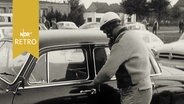 Autofahrer mit Helm besteigt seinen Wagen zur ADAC-Ostsee-Nordsee-Fahrt 1961  