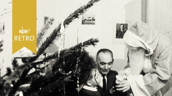 Weihnachtsmann gibt bei Familienbesuch einem Jungen ein Geschenk (1961)  
