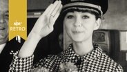 Schauspielerin Christine Kaufmann grüßt bei Besuch auf der "Bremen" mit Kapitänsmütze (1962)  