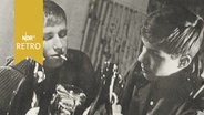Foto zweier Jugendlicher am Kneipentisch mit Bierflaschen und Zigarette (1962)  