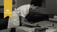 Modedesignerin fertigt in ihrem Atelier eine Skizze (1962)  
