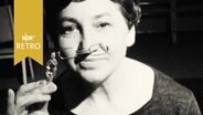 Frau probiert einen Zwicker aus (1962).  