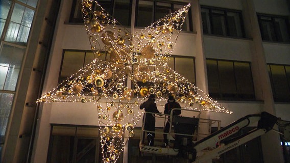 Zwei Männer installieren Weihnachtsbeleuchtung. © NDR 