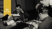 Mehrere Männer an einem Büchertisch in einer Bibliothek beim Lesen (1962)  