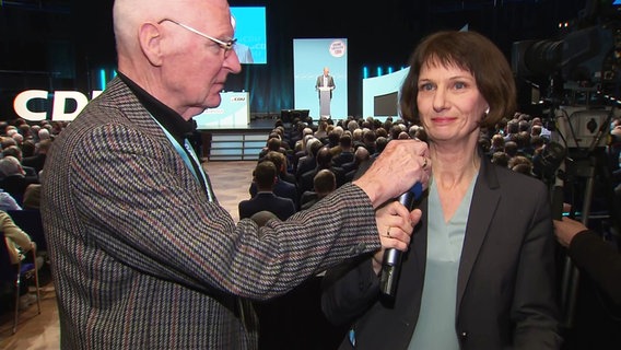 Bei der der Vorstellung des CDU-Grundsatzprogramms greift ein CDU-Mitglied der NDR Reporterin Katharina Seiler ins Mikrofon. © Screenshot 