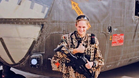 Corinna Kirchhöfer als Soldatin in Uniform mit Maschinengewehr vor einem Helikopter stehend. © Corinna Kirchhöfer 