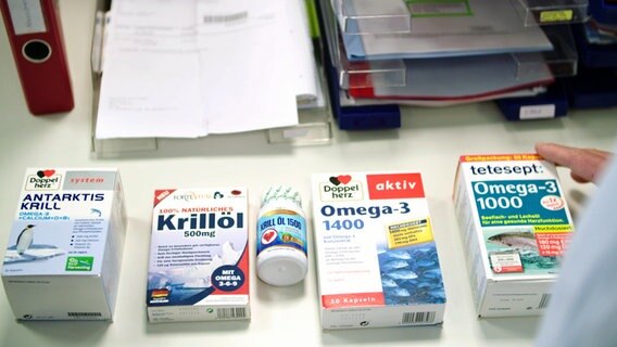 Fünf Packungen mit Omega-3-Fettsäure-Präparaten verschiedener Hersteller liegen auf einem Schreibtisch. © NDR/HTTV 