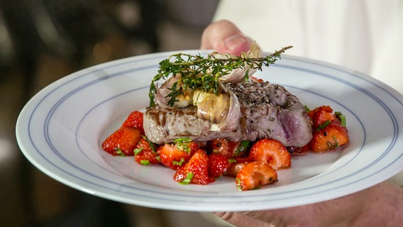 Teller mit gepfefferten Erdbeeren und einem Rinderfilet darauf. © NDR 