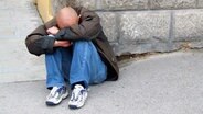 Verzweifelter Mann sitzt am Bürgersteig © imago/INSADCO 