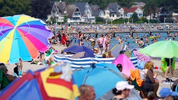Voller Strand von Travemünde. Im Vordergrund zahlreiche Sonnenschirme. Im Wasser viele Menschen. Im Hintergrund Häuser. © picture alliance/dpa Foto: Marcus Brandt