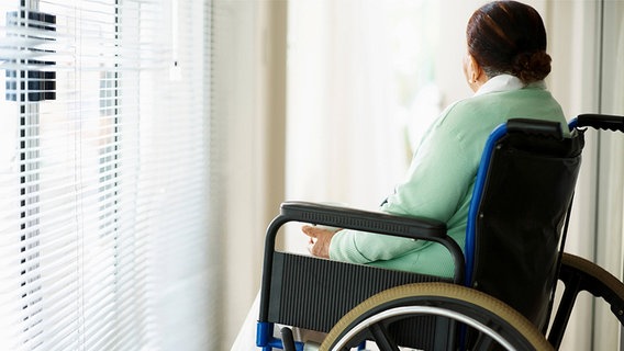 Rückansicht einer Patientin in einem Rollstuhl © imago/INSADCO 