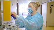 Eine Frau in Corona-Schutzkleidung auf einem Krankenhaus-Flur © NDR 
