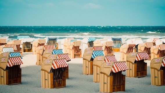 Strandkörbe am Strand, dahinter aufgewühlte See. © jock + scott / Photocase 