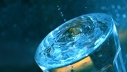 Sehr volles Wasserglas, von dem ein paar Tropfen hochspritzen. © Colourbox Foto: -