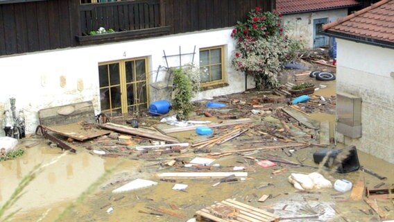 Blick auf einen überschwemmten Hof, in dem Müll und Treibgut schwimmen. © NDR/SpiegelTV 