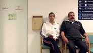 Michel Abdollahi (l.) sitzt mit einem Mann vor einer Tür in einer Rehaklinik. © NDR 