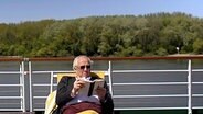 Hans-Jürgen Börner liest an Deck eines Kreuzfahrtschiffes. © NDR 