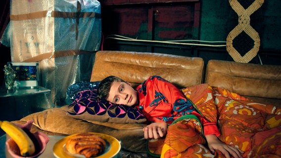 Zlatan (Noah Karayar) liegt mit traurigem Blick auf einem Sofa. © NDR/Agnesh Pakozd Foto: Agnesh Pakozd