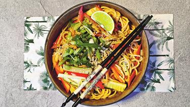 A bowl of peanut butter and garlic pasta is arranged on a placemat with chopsticks.  © Sebastian Maas 