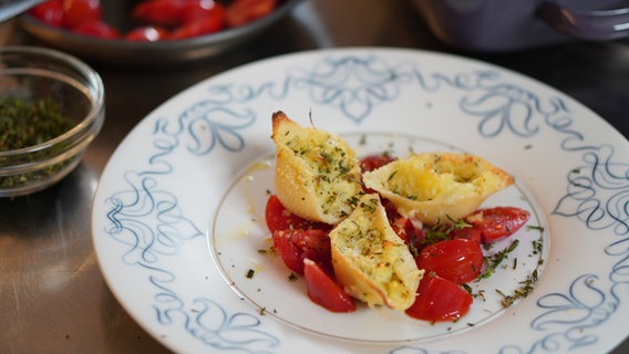 Drei gefüllte Conchiglioni (Muschelnudeln) sind mit Tomaten auf einem Teller angerichtet. © NDR Foto: Florian Kruck