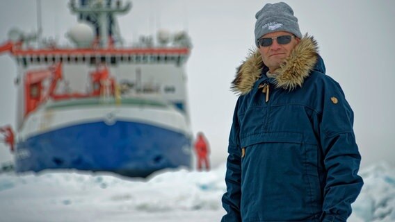 Marcus Rex steht vor einem Schiff im Polarmeer © Marcus Rex 
