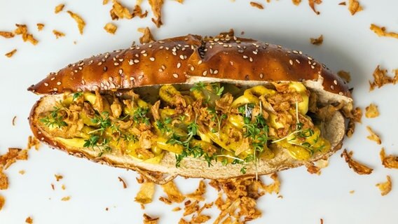 Ein veganer Hotdog mit Apfel-Senfsoße und süß-sauren Zwiebeln. © Organic Garden 