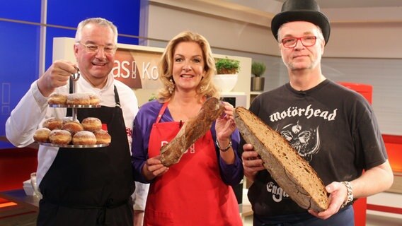 Rainer Sass, Bettina Tietjen und Jochen Gaues halten Berliner und Brote in die Kamera © NDR/dmfilm/Florian Kruck 