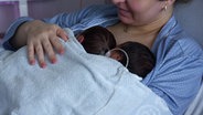 Zwei Neugeborene Babys liegen auf der Brust der Mutter © NDR.de 