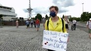 Karoline Preisler von der FDP steht mit Mundschutz und einem Schild auf einem Platz © NDR Foto: Screenshot
