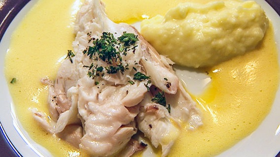 Fischfilet mit Orangensoße und Püree auf einem Teller serviert. © NDR 