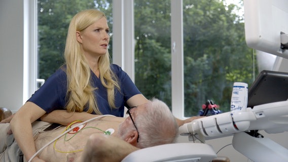Melanie Hümmelgen untersucht Patient auf einer Liege mit Ultraschall. © NDR 