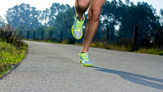 Runner with neon yellow sports shoes trains on a paved path © colourbox Photo: homydesign