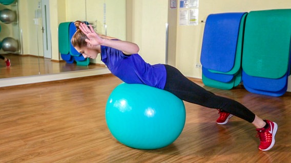 Svea Köhlmoos ziegt ein Schultertraining auf einem Gymnastikball © NDR 