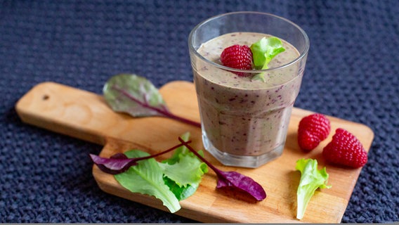 Smoothie mit Himbeeren und Salat auf einem Holzbrett. © NDR Foto: Claudia Timmann