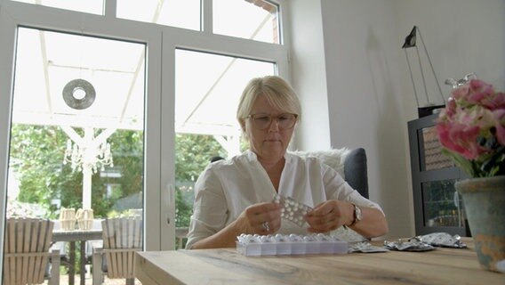 Eine Frau sitzt am Tisch und sortiert ihre Tabletten für die Woche in eine Pillenbox. Eine Frau sitzt am Tisch und sortiert ihre Tabletten für die Woche in eine Pillenbox. © NDR
