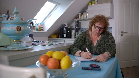 Frau sitzt am Küchentisch und führt Ernährungstagebuch. © NDR Foto: Moritz Schwarz/Oliver Zydek