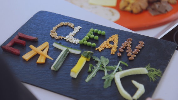 Gemüsestückchen auf einer Schiefertafel bilden Buchstaben und damit den Begriff "Clean Eating". © NDR Foto: Oliver Zydek/Moritz Schwarz