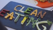 Gemüsestückchen auf einer Schiefertafel bilden Buchstaben und damit den Begriff "Clean Eating". © NDR Foto: Oliver Zydek/Moritz Schwarz