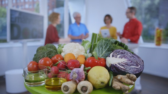 Die vier Ernährungs-Docs im HIntergrund am Stehtisch, vorn ein Korb mit Gemüse © NDR Foto: Moritz Schwarz/Oliver Zydek