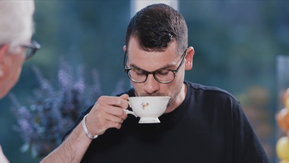 Doc Klasen schaut zu, wie sein Patient vorsichtig an einer Tasse Tee nippt. Doc Klasen schaut zu, wie sein Patient vorsichtig an einer Tasse Tee nippt. © NDR Foto: Oliver Zydek/Moritz Schwarz