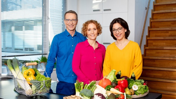Die Ernährungs-Docs Matthias Riedl, Viola Andresen und Silja Schäfer stehen hinter dem Küchentresen in der Hausboot-Praxis. © NDR Foto: Claudia Timmann